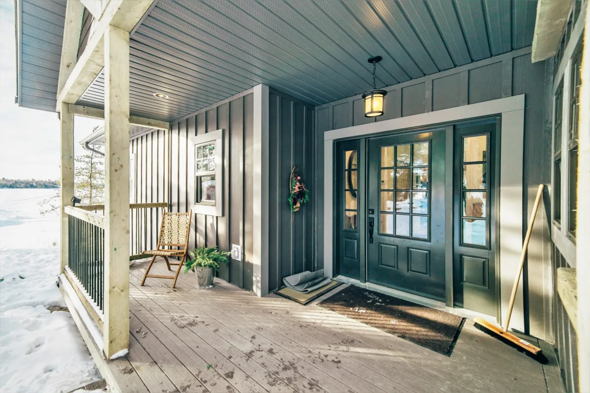 Gros plan sur un porche de maison avec une porte verte et un revêtement vert.