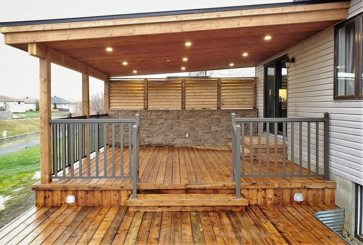 Deck en bois avec un mur d'intimité et un toit en pente.