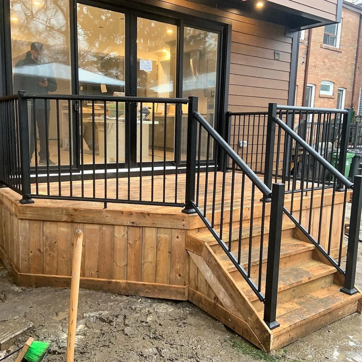 Escaliers extérieurs en bois avec une rampe métallique en PVC noir.