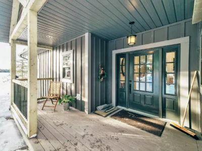 Close-up on a house porch with a green door and green siding.