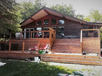 Cabin like house with treated wood siding, terrace and fence.