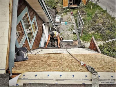 Man laying shingles on a sloped roof.