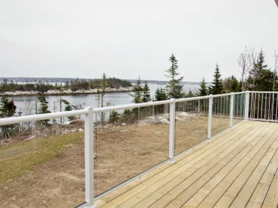 Wood terrace with glace fence facing a lake.