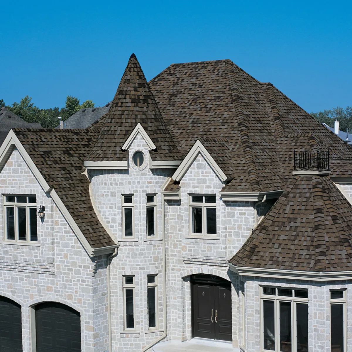 Impressive gray brick house with a turret and a burgundy brown roof BP