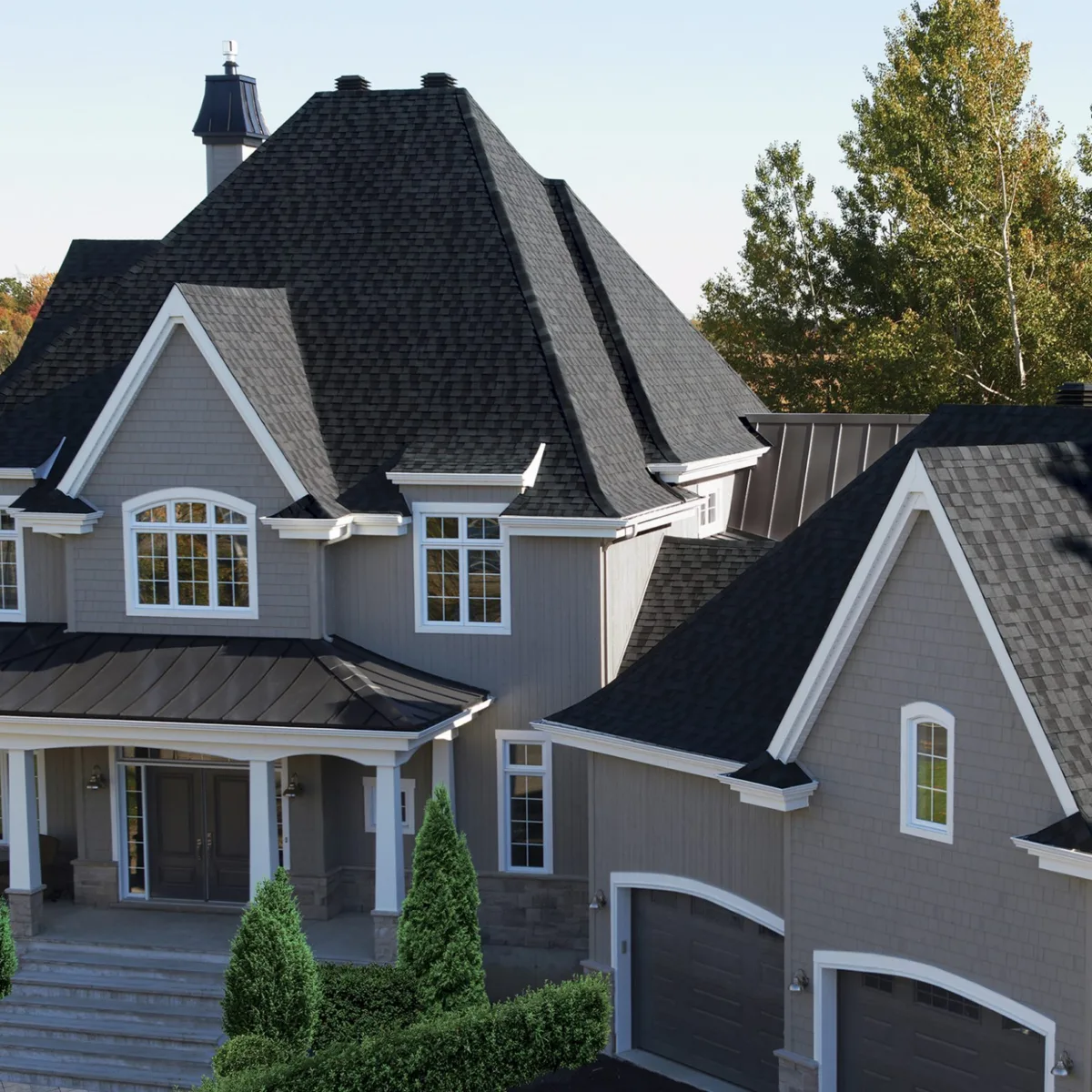 Luxiourious gray house with a separate double garage with black shingles.